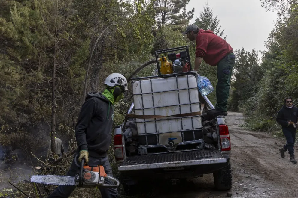 El fuego cruzó el río Azul y avanza sobre Camino 7 Suavos, vecinos mojan los terrenos para que las llamas no alcancen las viviendas (foto: Eugenia Neme)