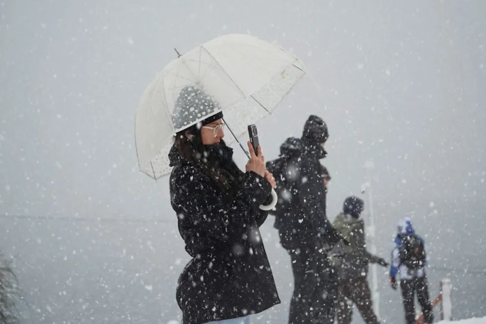 Sacando fotos bajo la nieve... pero con paraguas; los turistas disfrutan cada momento. 