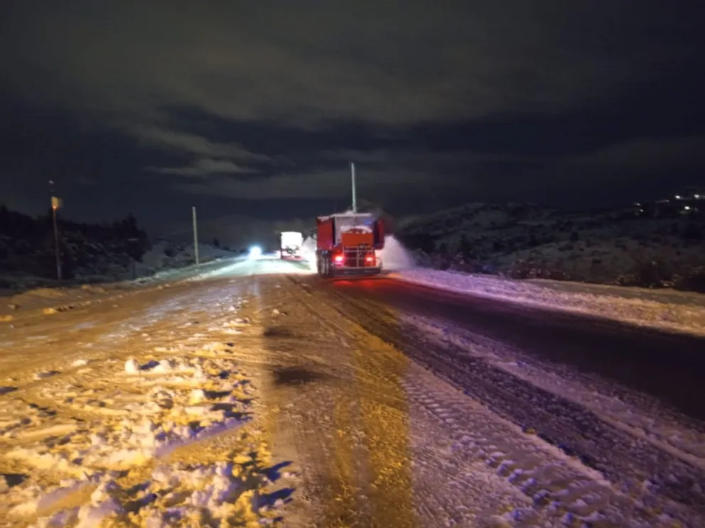 Tramos con nieve y hielo sobre la calzada, y maquinaria vial realizando tareas de mantenimiento. 